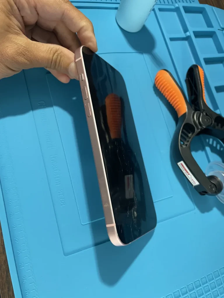 Technician opening an iPhone with a suction cup and pry tool on the YAS TECH repair bench