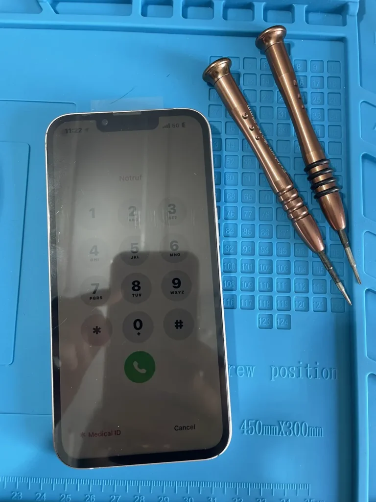 Phone on the repair mat next to precision screwdrivers